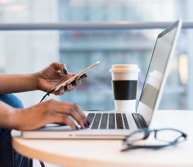 femme travaillant sur un ordinateur portable dans un bureau et prenant une tasse de café
