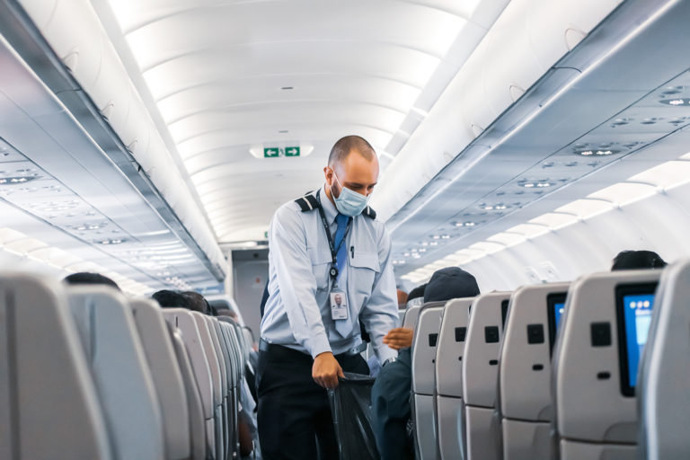 Airline staff member walking through the cabin of an airplane